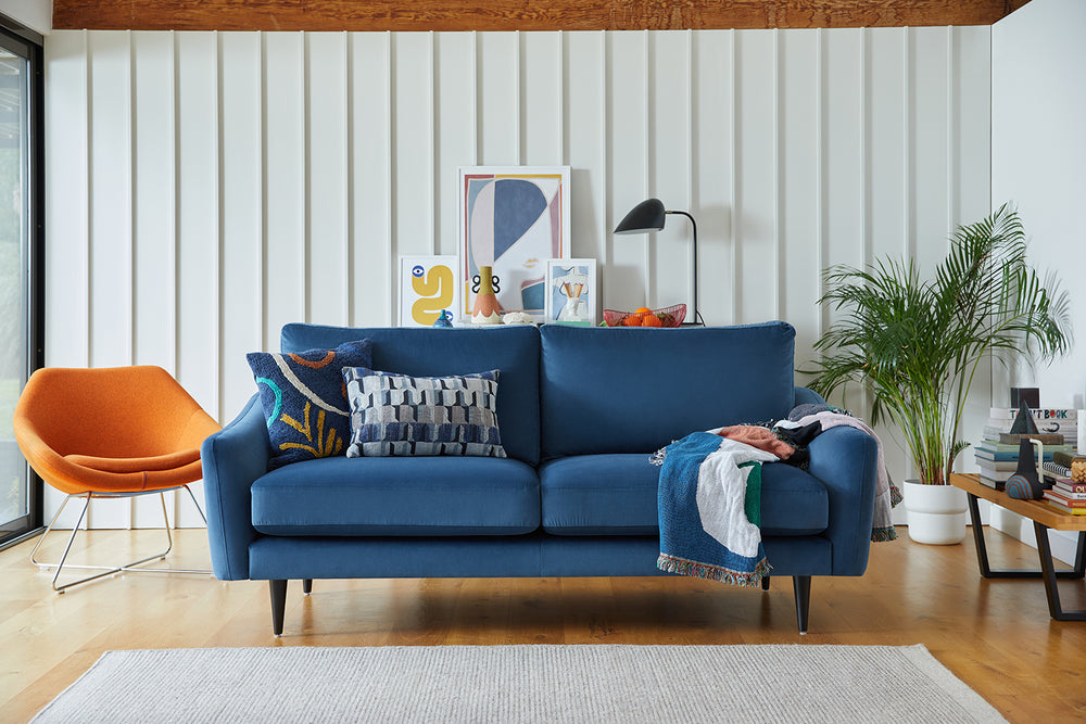 Mid Century Modern blue sofa with black wooden legs in a living room