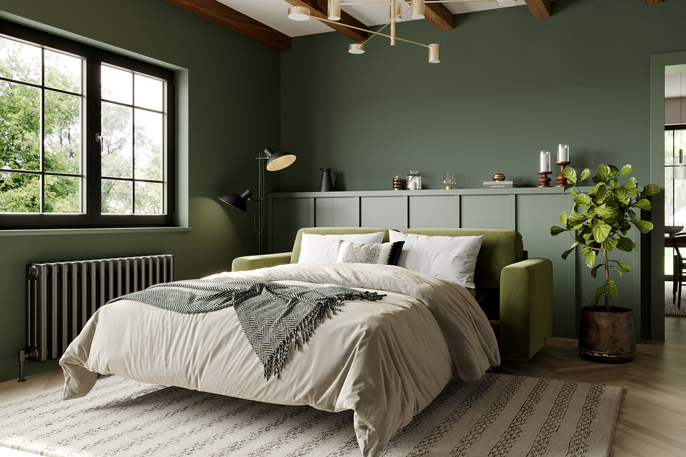 The Big Chill open sofa bed in olive green with neutral linens and green walls